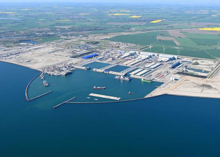 English: The Danish tunnel construction site. Several work vessels and a tunnel element are moored in the working harbour. // Dansk: Den danske tunnelbyggeplads. I arbejdshavnen ligger adskillige arbejdsskibe og en tunnelelement. // Deutsch: Die dänische Tunnelbaustelle. Im Arbeitshafen liegen etliche Arbeitsschiffe und ein Tunnelelement.