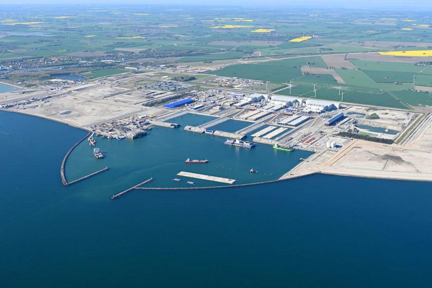 English: The Danish tunnel construction site. Several work vessels and a tunnel element are moored in the working harbour. // Dansk: Den danske tunnelbyggeplads. I arbejdshavnen ligger adskillige arbejdsskibe og en tunnelelement. // Deutsch: Die dänische Tunnelbaustelle. Im Arbeitshafen liegen etliche Arbeitsschiffe und ein Tunnelelement.
