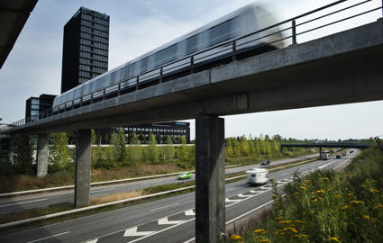 Die Kopenhagener Metro fährt auf einer Brücke über eine mehrspurige Straße.