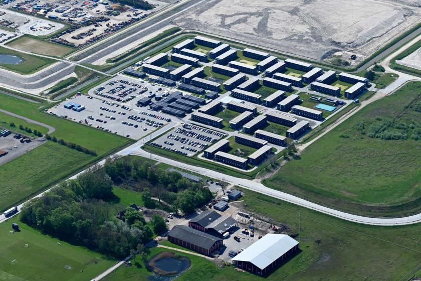Die Wohnanlage aus vielen aufeinander gestapelten Containern, die die einzelnen Zimmer bilden. Sie sind in viereckigen Blöcken aufgestellt, sodass in der Mitte jeweils ein Innenhof entsteht. Rund herum ist es grün.